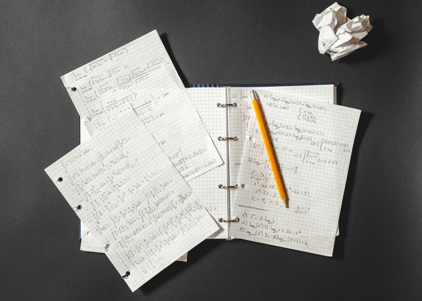 Mathematical Equations Written in a Notebook. Crumpled Piece of Paper on Black Desk.